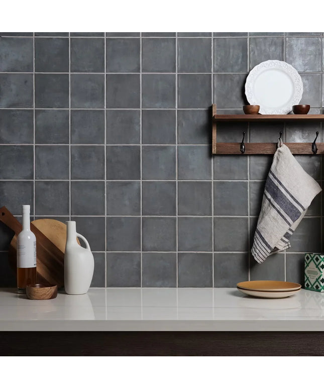 Kitchen with gray tiled wall, wooden shelf, and various kitchen items.