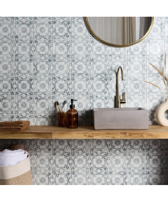 Bathroom with floral-patterned tiles, wooden vanity, and round mirror.