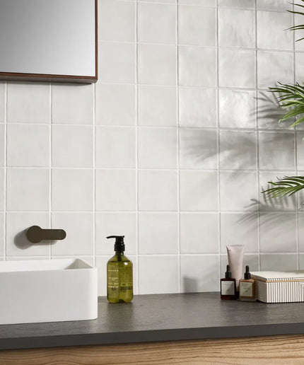 Bathroom counter with skincare products against a tiled wall