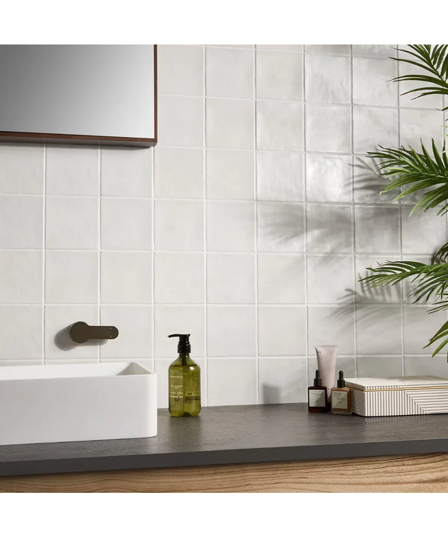 Bathroom counter with skincare products against a tiled wall