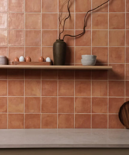 Terracotta tiles with a shelf displaying ceramic items against a matching wall.