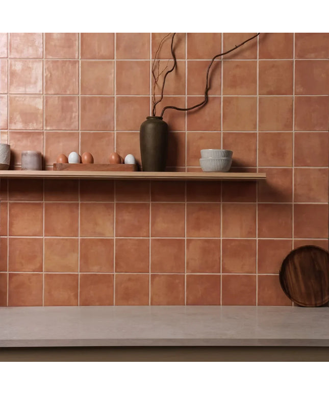 Terracotta tiles with a shelf displaying ceramic items against a matching wall.