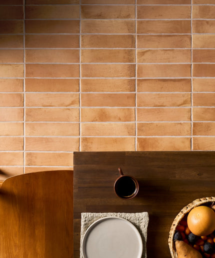 Peach terracotta wall tiles with a wood dining table and fruit basket