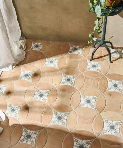Patterned floor tiles with a plant and draped fabric in the background