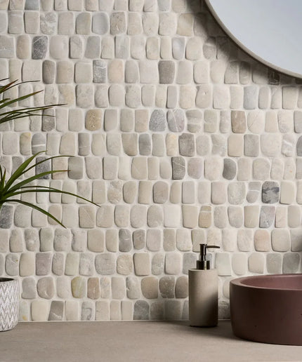 Bathroom with stone mosaic wall, plant, and sink.