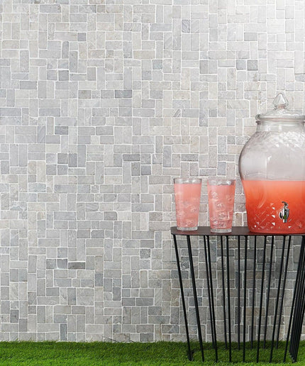 Antique natural stone wall tiles with geometric pattern behind drink dispenser and glasses