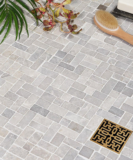 Antique natural stone mosaic tiles with decorative drain, ideal for bathroom or shower floors.