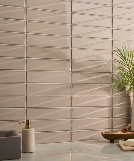 Beige tiles with geometric pattern in a bathroom setting with a plant and sink.
