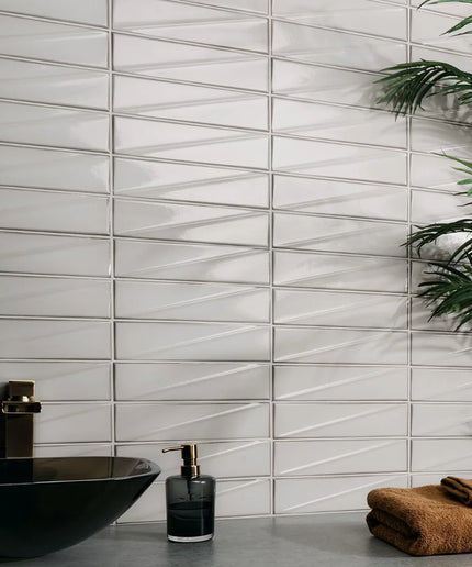 Bathroom setting with a tiled wall, black sink, and brown towels.