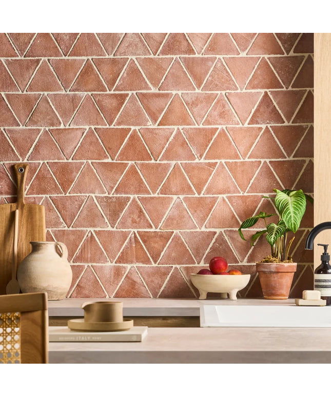 Kitchen with terracotta triangle-patterned tiles on the wall, wooden counter, and decorative items.