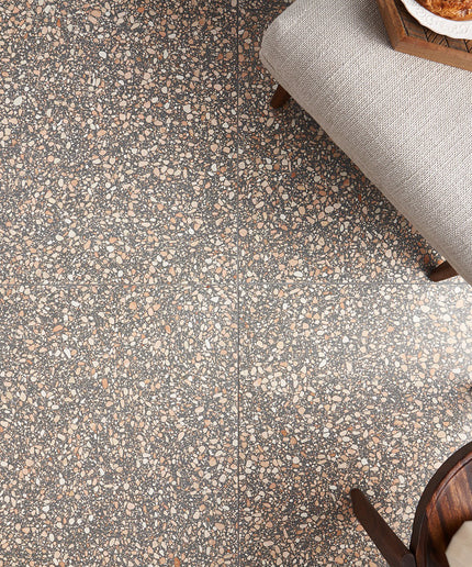 Terrazzo-style floor with speckled pattern and gray upholstered chair.