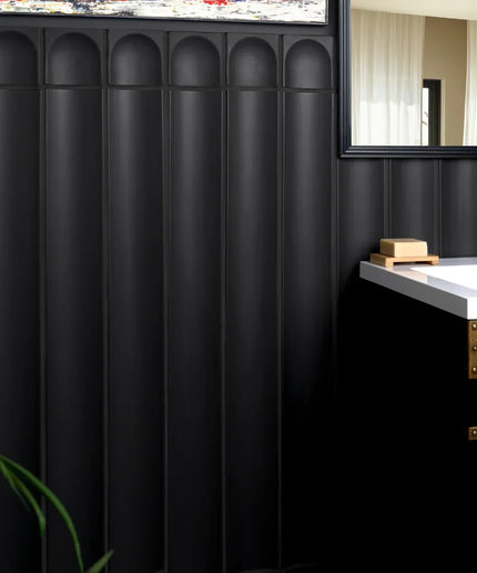 Matte black fluted column tiles on a bathroom wall beside a modern vanity and mirror.