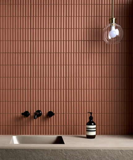 Bathroom with brown tiled wall, sink, and decorative bottle.