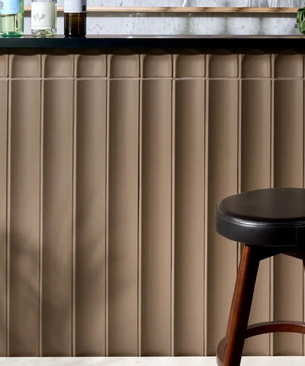 Taupe fluted column wall tiles with barstool and marble counter in modern kitchen setting