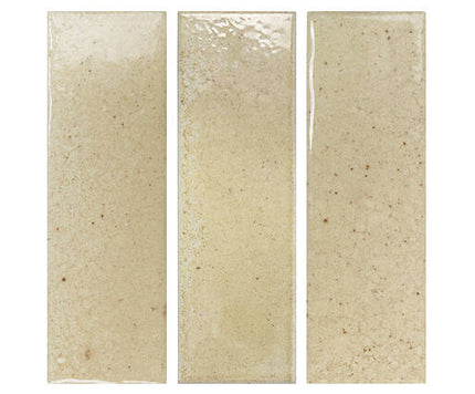 Three vertical rectangular ceramic subway tiles in a warm cream-beige glaze with subtle brown speckles, shown side-by-side on a white background.