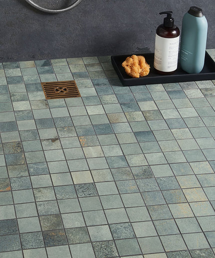 Tile floor with a shower drain and bath products on a tray