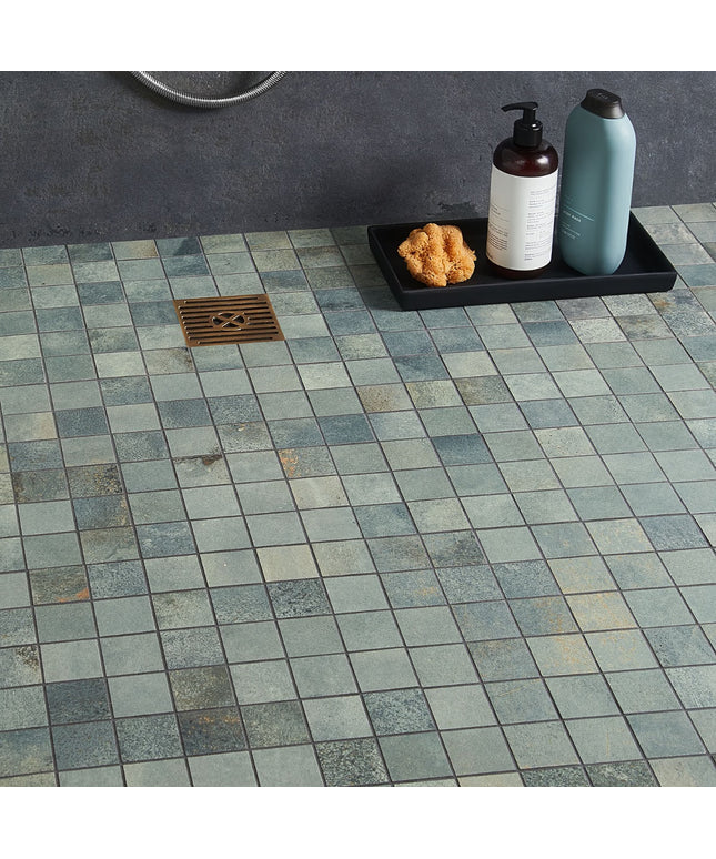 Tile floor with a shower drain and bath products on a tray