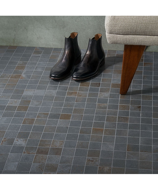 Pair of black leather boots on a tiled floor with a chair in the background
