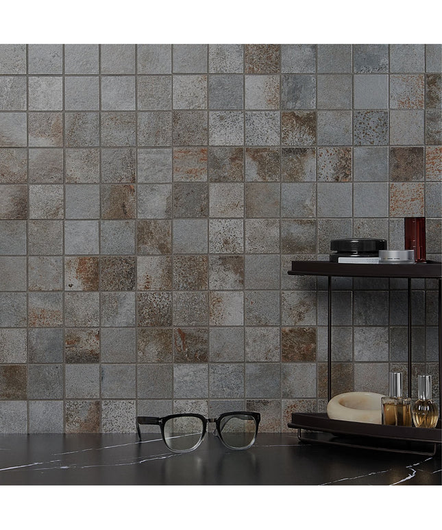 Mosaic tile wall with a dark countertop and glasses in front