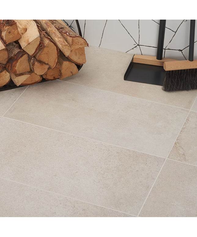 Tile floor with stacked firewood and cleaning tools against a tiled wall.
