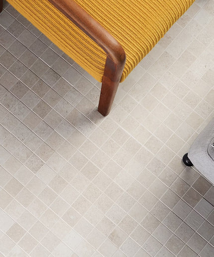 Close-up of a tiled floor with a yellow chair and gray suitcase. made in the USA