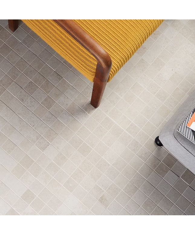 Close-up of a tiled floor with a yellow chair and gray suitcase. made in the USA