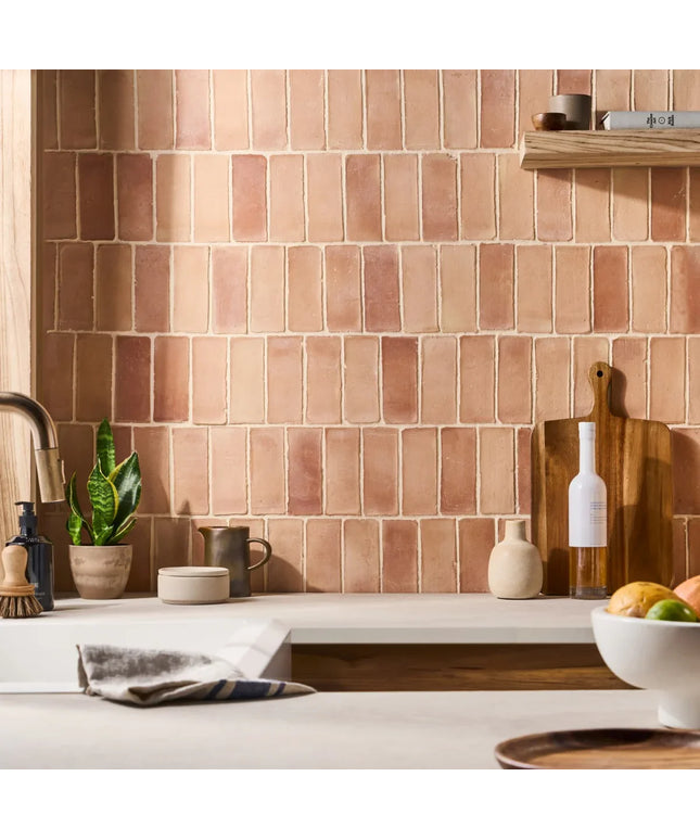 Kitchen with terracotta tiled wall, countertop items, and a wooden cutting board.