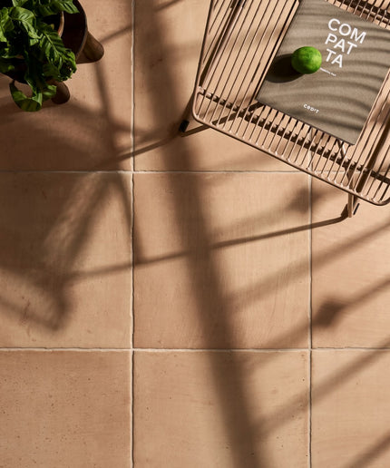 Sand beige 18x18 floor tiles with natural finish, styled with a plant and metal chair.
