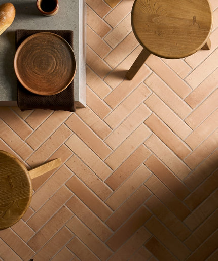Sand fuego terracotta floor tiles in herringbone pattern with wooden stools and table