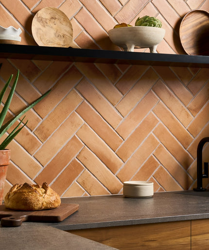 Sand and terracotta herringbone wall tiles in a modern kitchen backsplash setting.