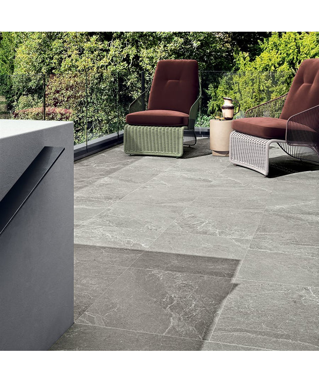Outdoor patio with gray tiles, chairs, and a garden view.