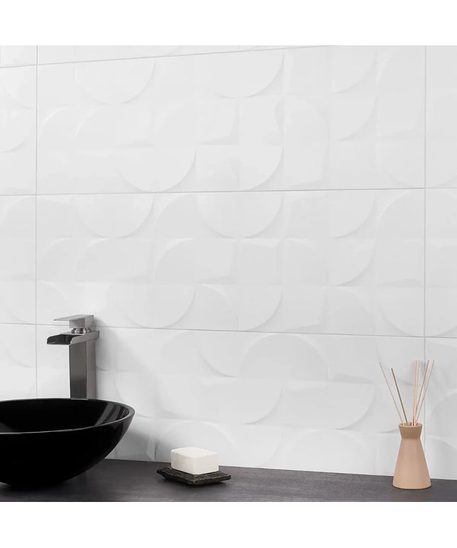 Bathroom setting with a black sink, soap, and diffuser against a white tiled wall.