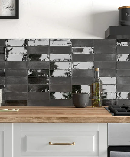 Glossy black 2x6 wall tiles as kitchen backsplash with wood countertop and modern decor