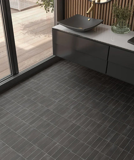 Modern bathroom with black matte 2x6 floor tiles, floating vanity, and glass door