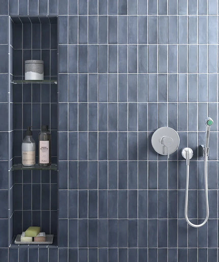 Blue gloss 2x6 wall tiles in a modern shower with built-in shelves and chrome fixtures