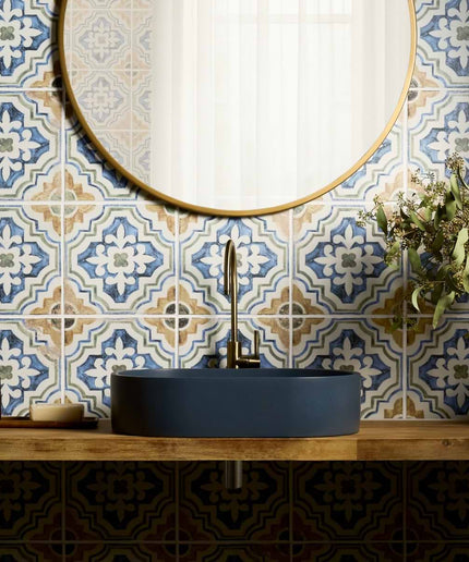 Patterned blue and beige ceramic bathroom tiles with vessel sink and round mirror