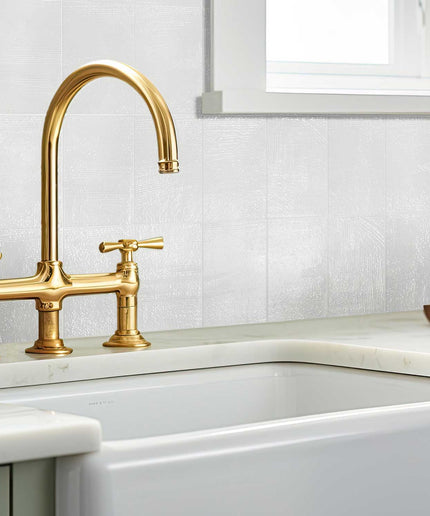 Modern kitchen with glossy white 3x7 porcelain wall tiles and gold faucet by window