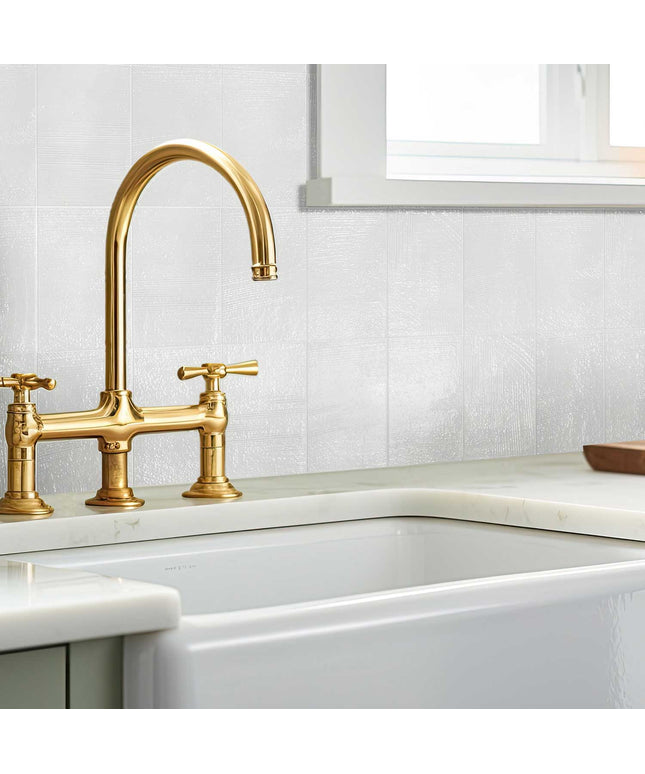 Modern kitchen with glossy white 3x7 porcelain wall tiles and gold faucet by window