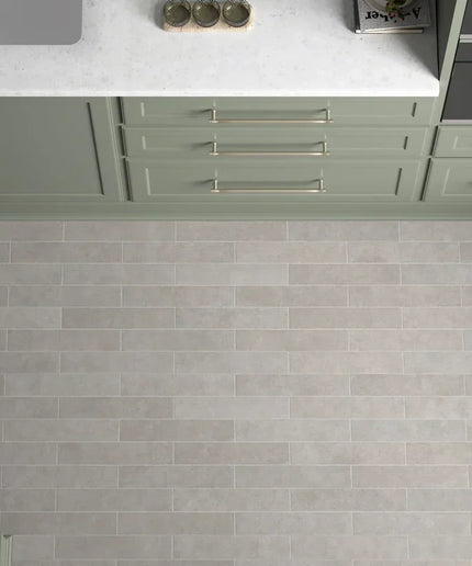 Stage grey matte 2.5x12 tile on kitchen floor with green cabinets and white countertop