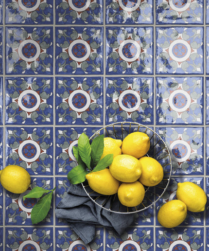 Decorative blue patterned tiles with a wire basket of fresh lemons and green leaves