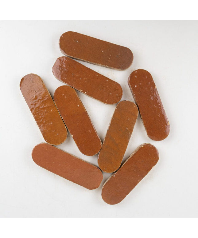 Sundried clay 2x6 oval tiles with glossy finish on a white background