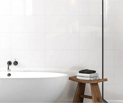 super white wall tiles modern bathroom with a freestanding bathtub and wooden stool with towels.