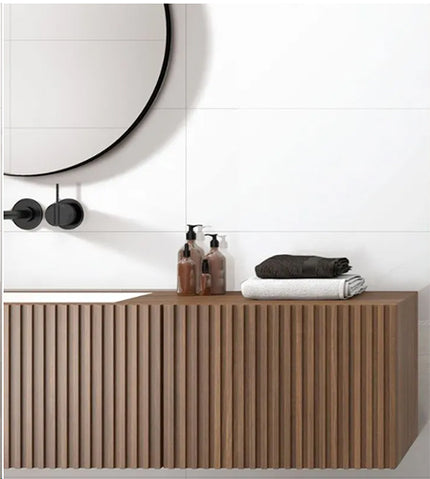 Bathroom vanity with toiletries and towels against a white tiled wall.