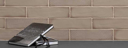Two black notebooks stacked on a surface with a taupe subway tiled wall background