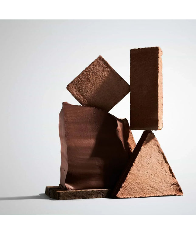 Abstract sculpture made of brown rectangular blocks on a light gray background