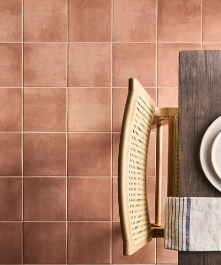 Brown tiled wall with a wooden chair and table setting.