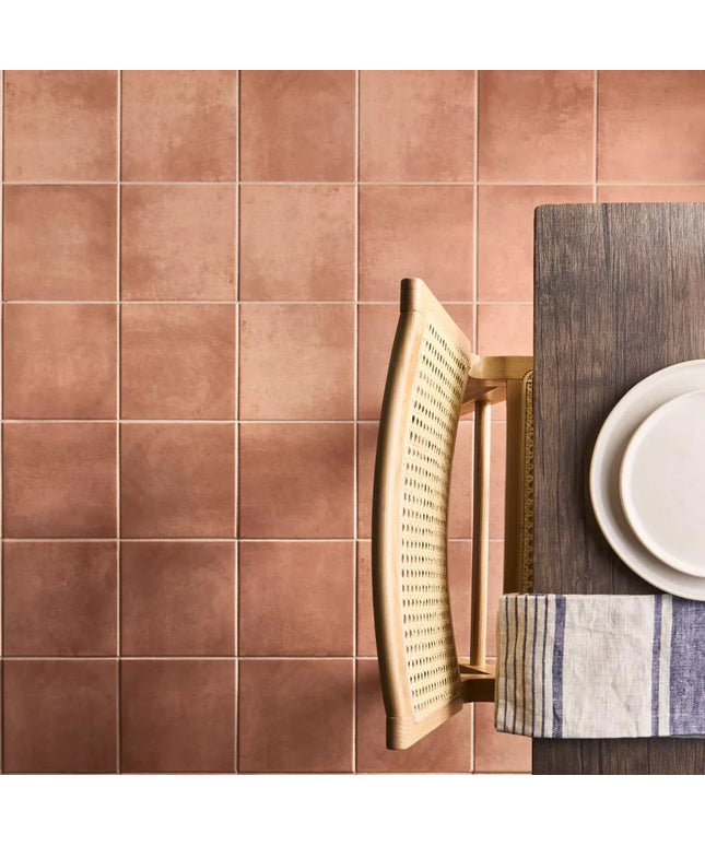Brown tiled wall with a wooden chair and table setting.