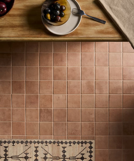 Brown tiled floor with a wooden table and plate of grapes in the background