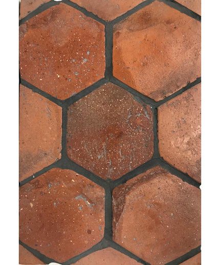 Hexagon terracotta floor tiles with a rustic, earthy red finish and textured surface.