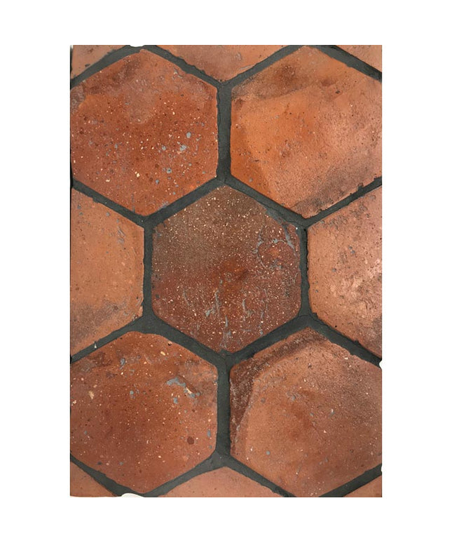 Hexagon terracotta floor tiles with a rustic, earthy red finish and textured surface.